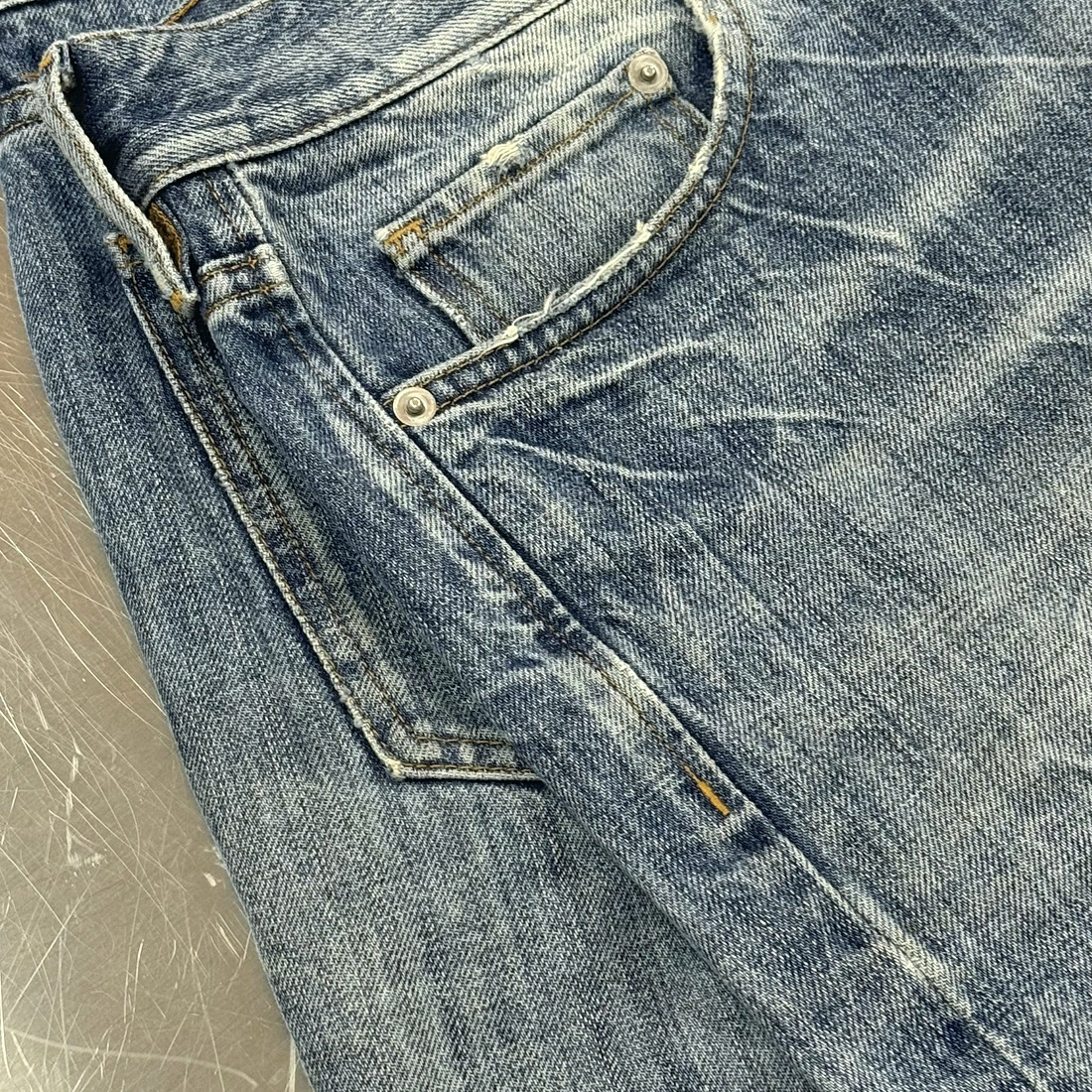 Denim waistband and hardware on a steel table