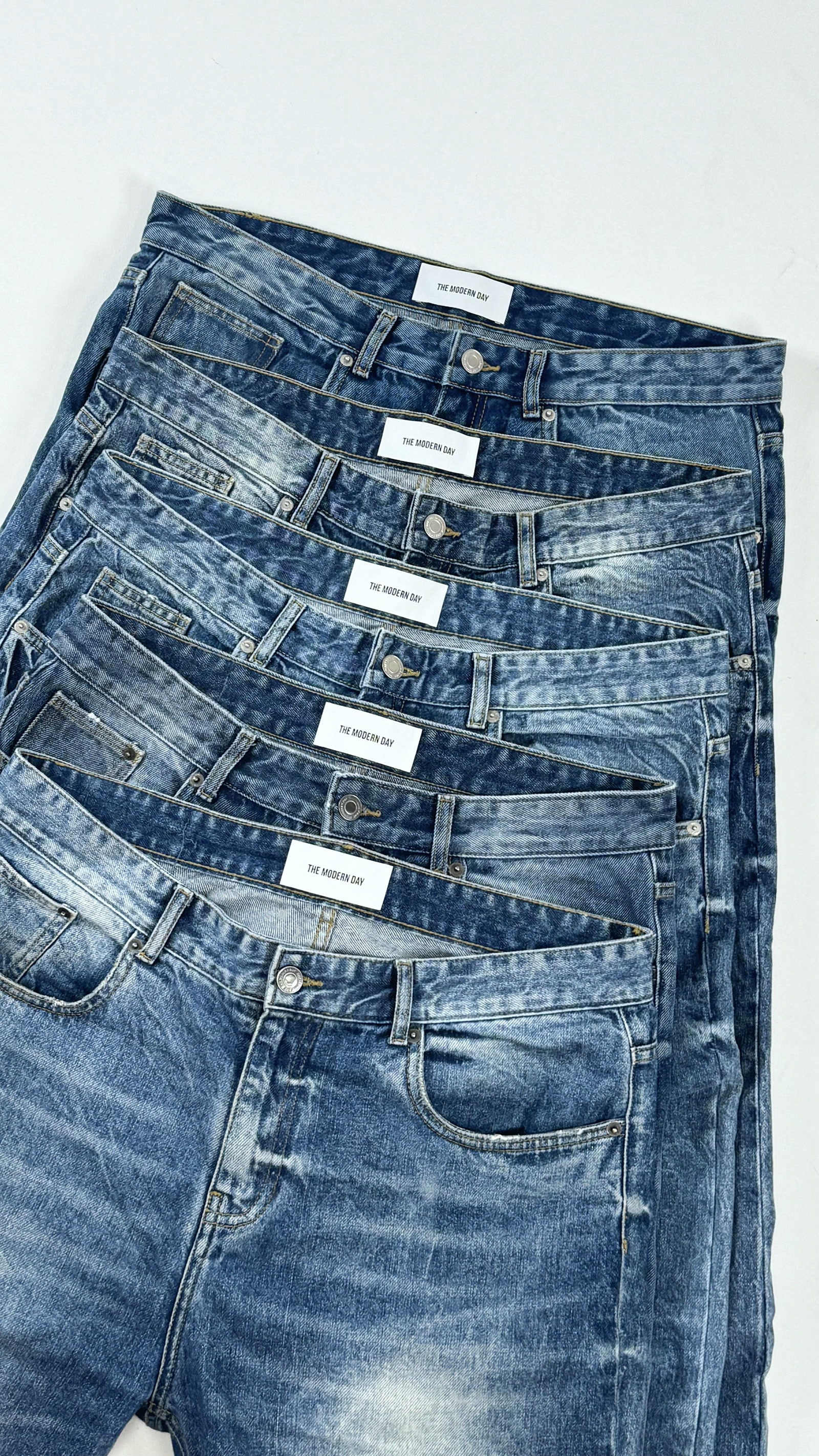 THE MODERN DAY washed denim, folded and stacked, each with a label